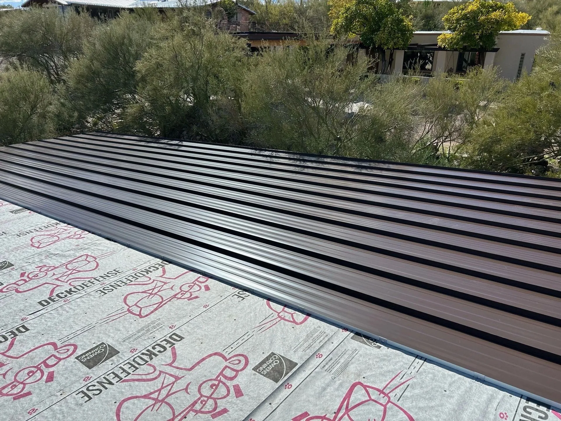 Charcoal snap-lock standing-seam panels laid on roof deck during a real Arizona install