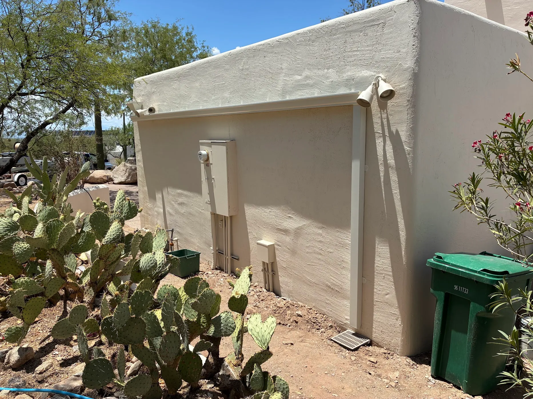 Tan seamless gutter and rectangular downspout color-matched to a stucco home corner