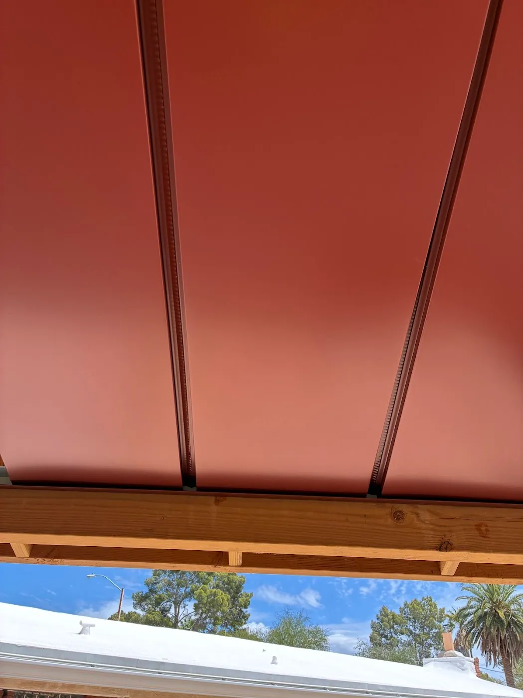 Looking up at a finished red standing seam patio cover ceiling