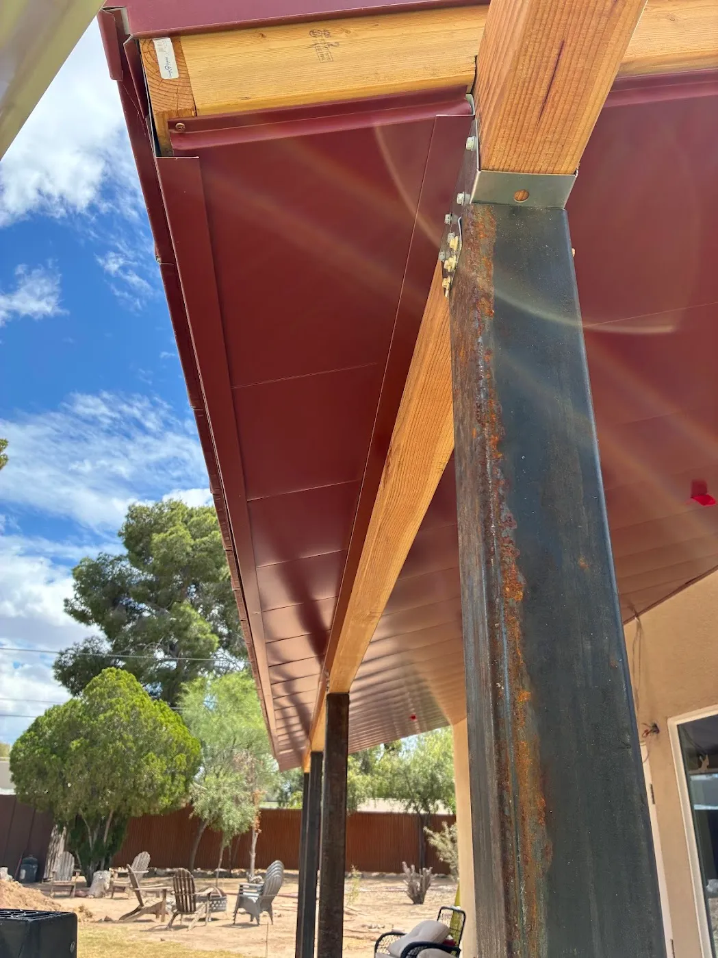 Red metal patio cover edge detail at the fascia, steel post column and wood beam connection
