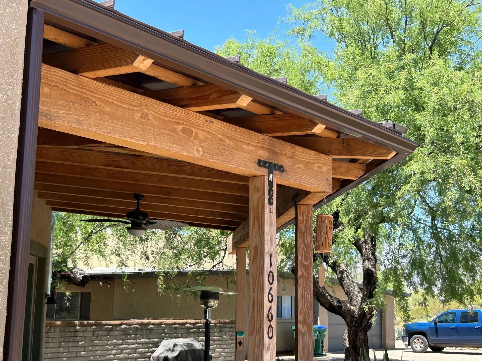 Wood-grain printed metal patio cover detail showing warm cedar-tone finish on snap-lock panels