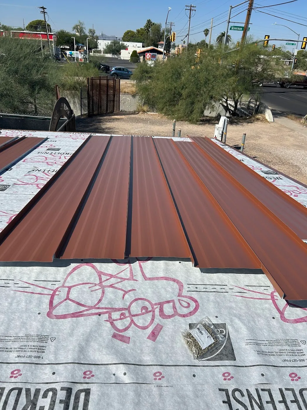 Copper-tone standing seam panels being installed on a roof deck over DeckDefense underlayment