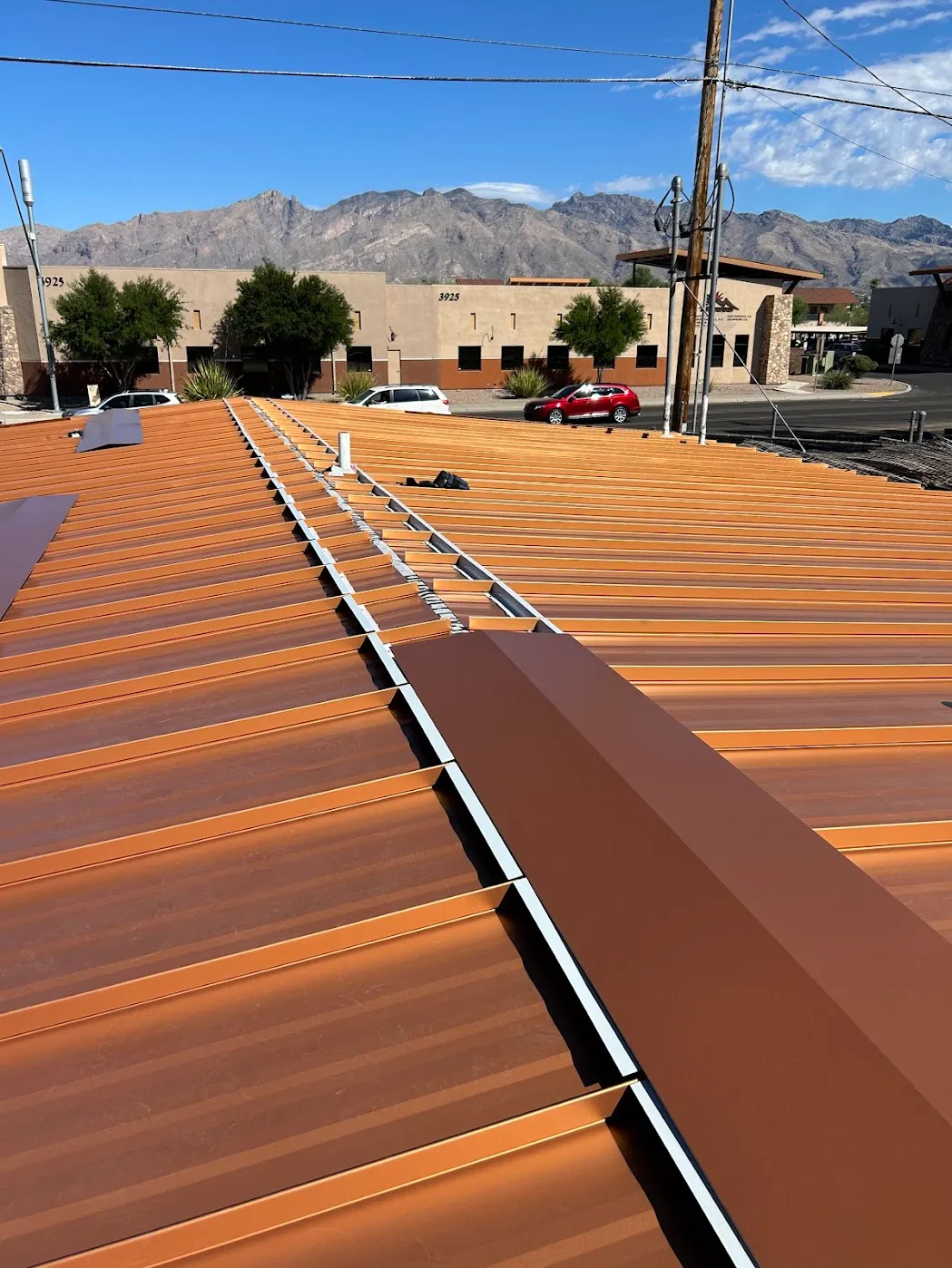 Finished copper-tone standing seam roof on a Tucson commercial building, panel run and ridge visible