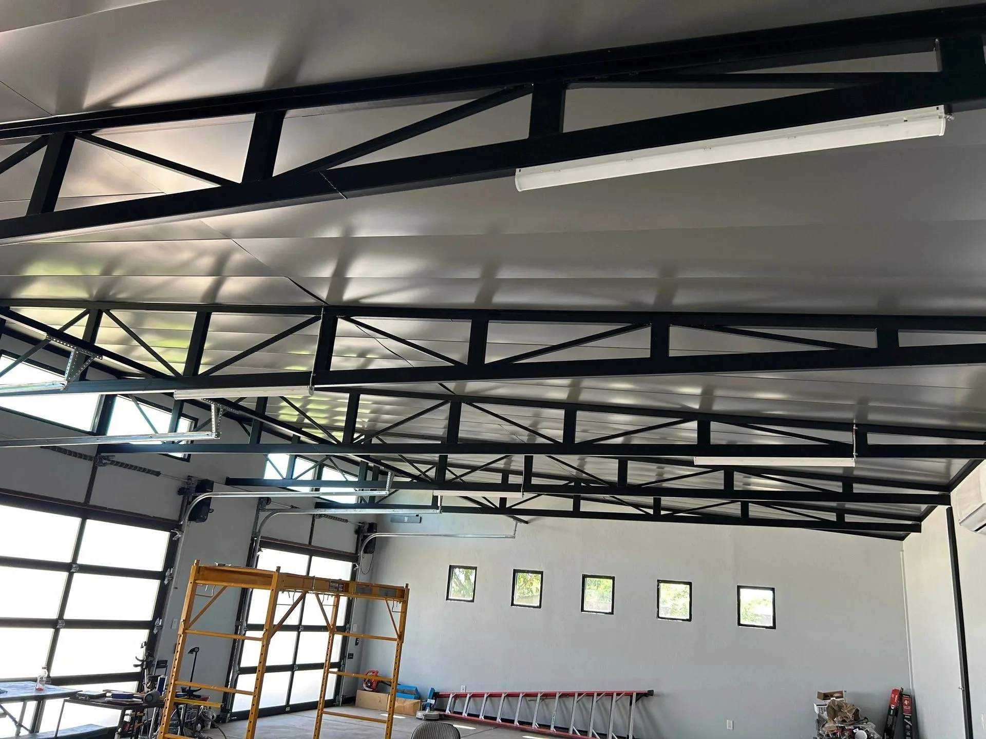 Finished Arizona shop interior with black steel trusses and white metal under-decking spanning the full bay