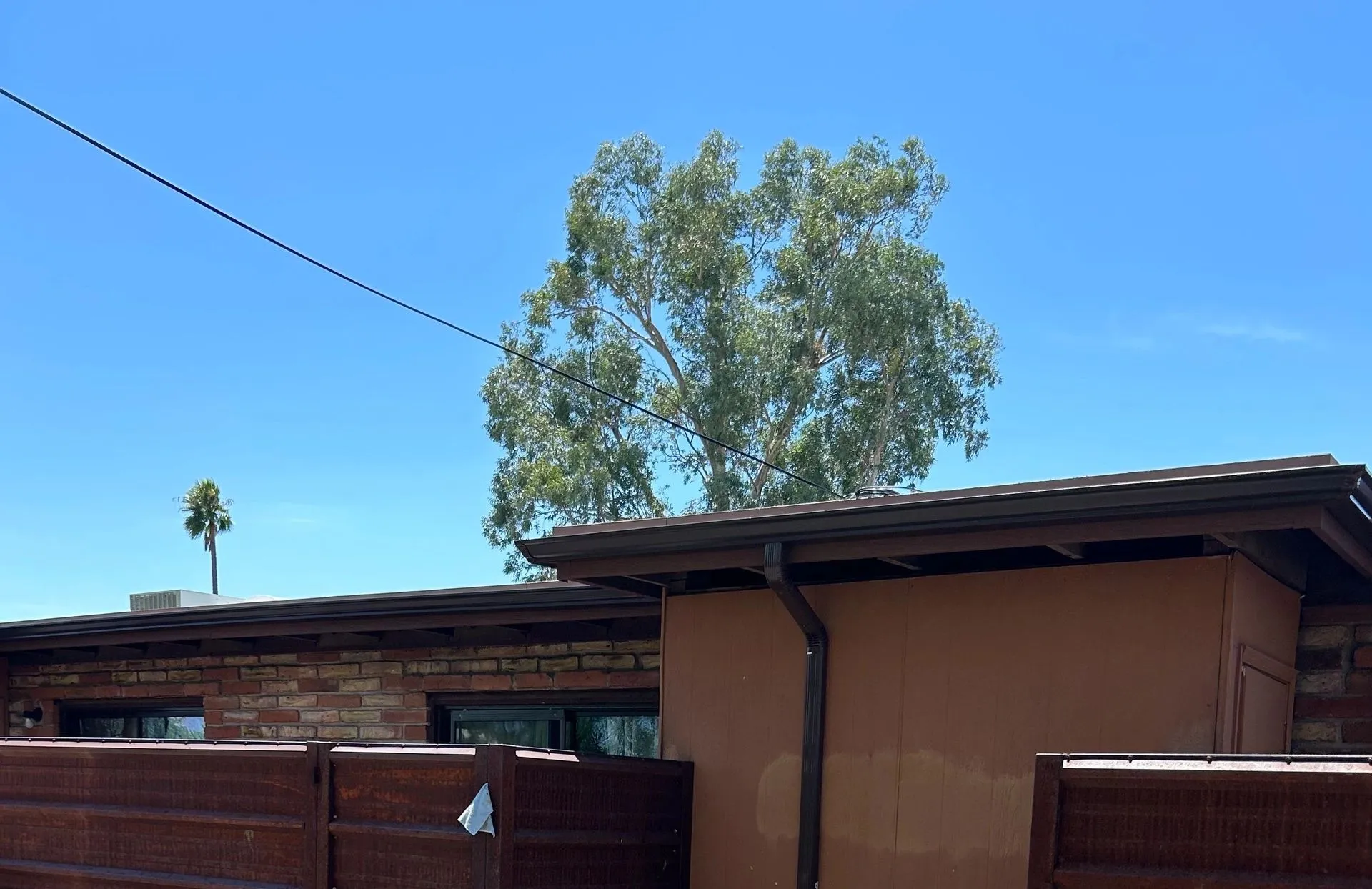 Tucson home with brown standing-seam metal roof, recent chop-and-drop delivery