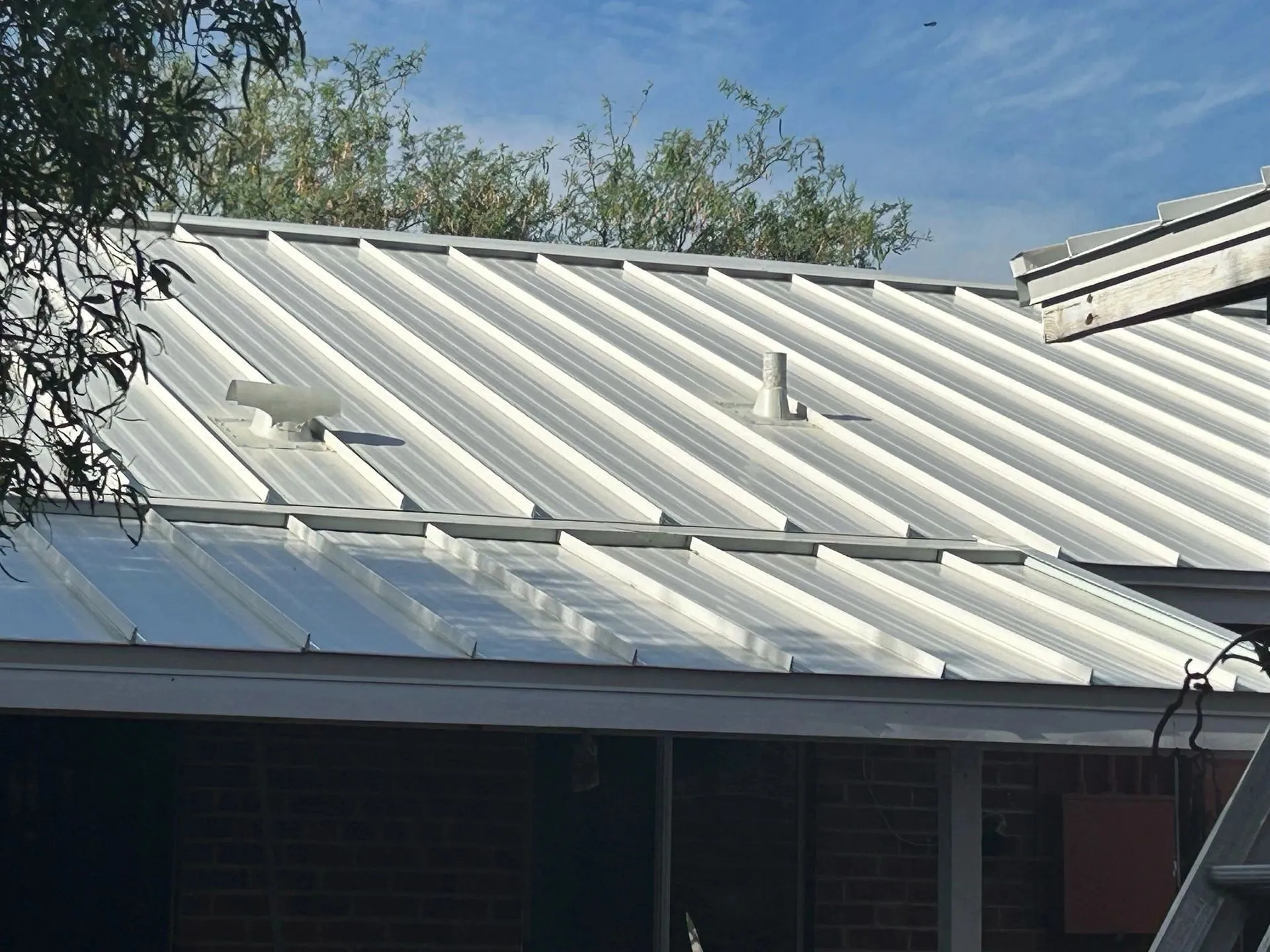 Close-up of white standing-seam panels with ridge cap on an Arizona home